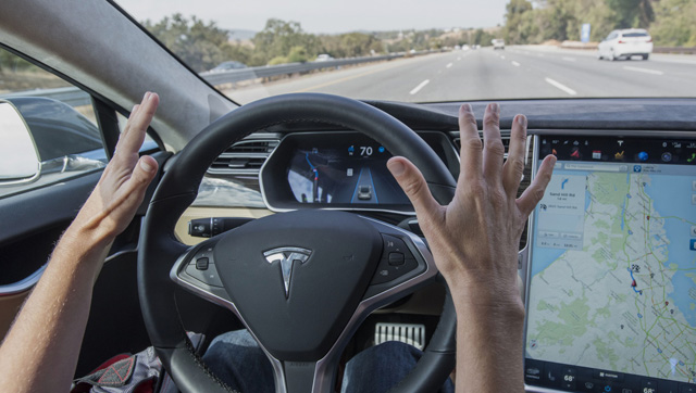 A member of the media test drives a Tesla Motors Inc. Model S car equipped with Autopilot in Palo Alto, California, U.S., on Wednesday, Oct. 14, 2015. Tesla Motors Inc. will begin rolling out the first version of its highly anticipated "autopilot" features to owners of its all-electric Model S sedan Thursday. Autopilot is a step toward the vision of autonomous or self-driving cars, and includes features like automatic lane changing and the ability of the Model S to parallel park for you. Photographer: David Paul Morris/Bloomberg via Getty Images